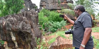 A local tourist takes a photo of the black rock at Chasimba Caves in Kilifi County.