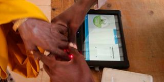 A polling clerk uses a Kiems kit to identify a voter at Wajir Girls High School.