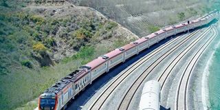 A passenger train travels along the standard gauge railway line at Miritini Station.