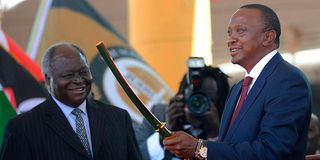 Kenya's fourth president Uhuru Kenyatta receives a sword as a symbol of authority from his predecessor Mwai Kibaki