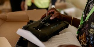 An IEBC official inspects a Kenya Integrated Election Management System (KIEMS) kit in a bag in Kisumu