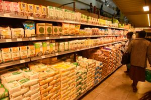 Customers countercheck the prices of maize flour at a supermarket in Nakuru City
