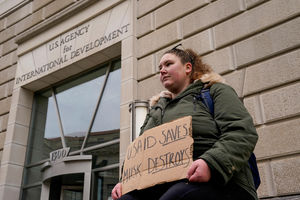 woman holds a placard outside the USAID building